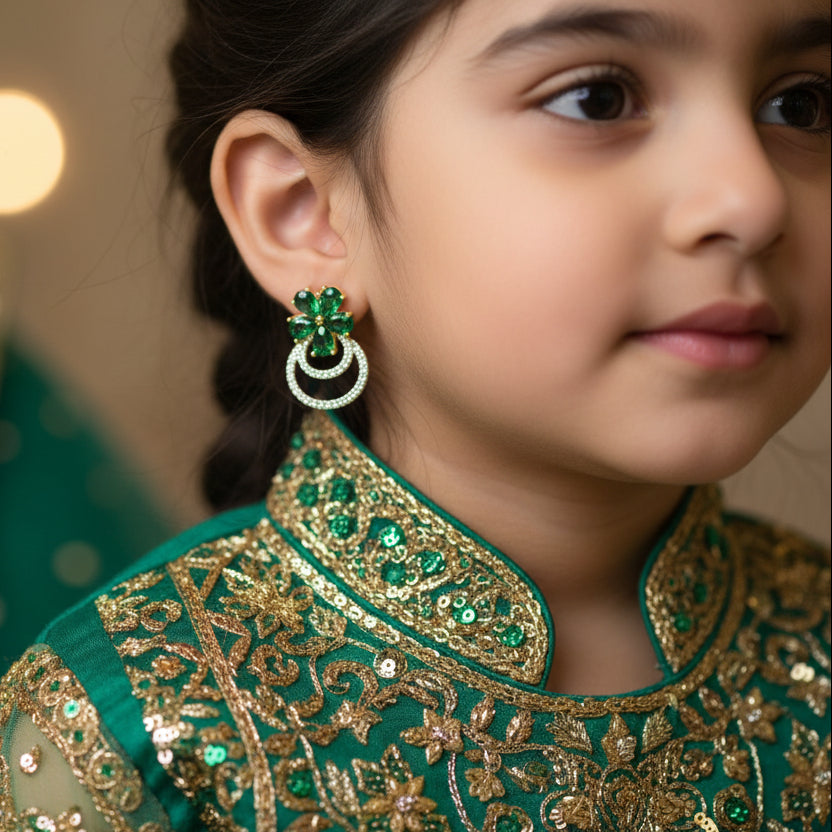 Pair of earrings with green gemstones on a gray surface
