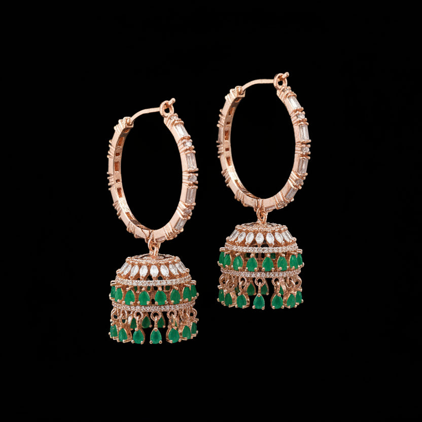 Gold and green earrings on a gray stand with 'Saheli' branding.