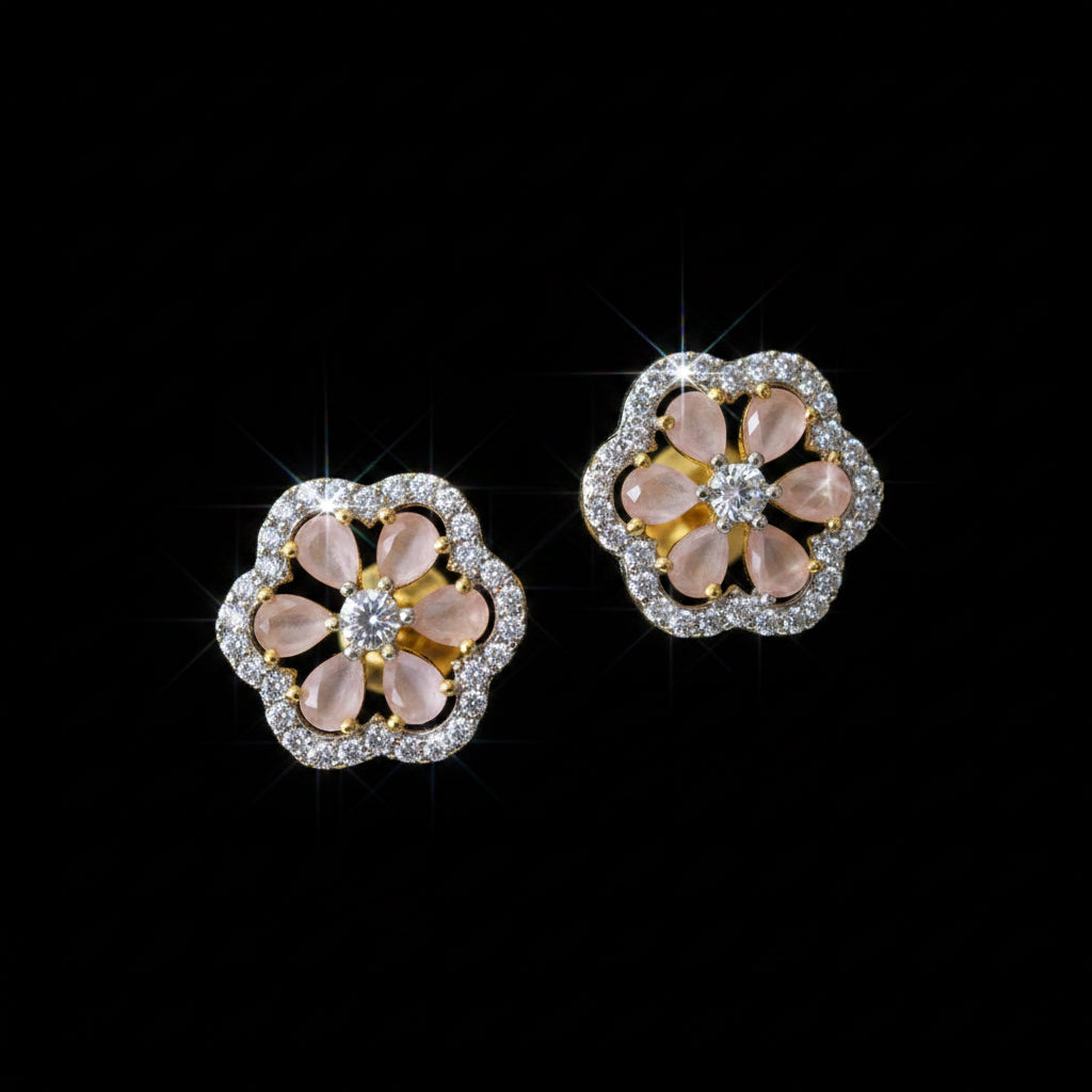 Flower-shaped earrings with pink and gold colors on a gray surface