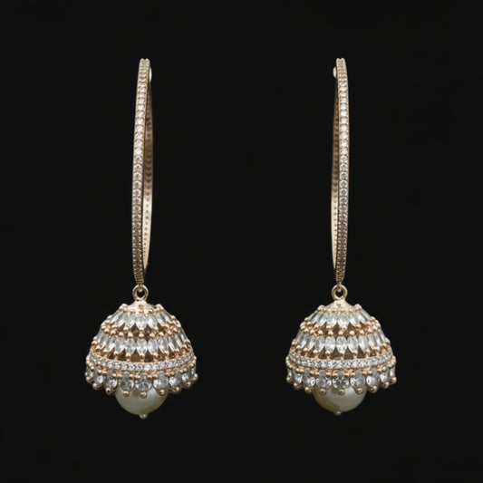 Gold hoop earrings with spherical embellishments on a black stand against a dark background.