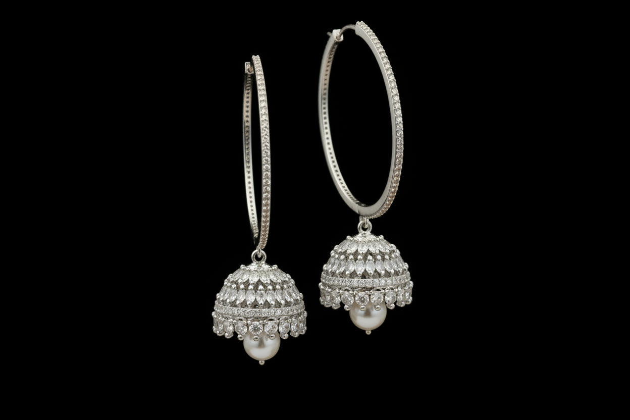 Gold hoop earrings with spherical embellishments on a black stand against a dark background.