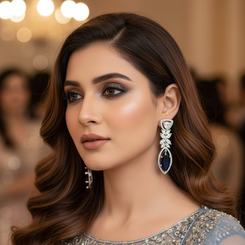 Diamond earrings with blue gemstones on a gray background, branded 'Saheli'.