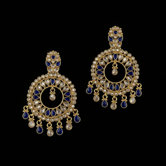 A pair of gold-plated Indian chandelier earrings with deep blue stone accents and clear stones, displayed on a dark reflective surface with the brand logo 'SAHELL MY BEST FRIEND' at the top.