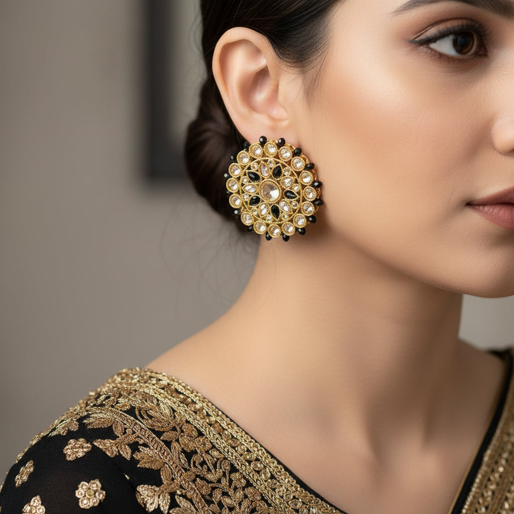 Gold and black earrings with SAHELI branding on a dark background