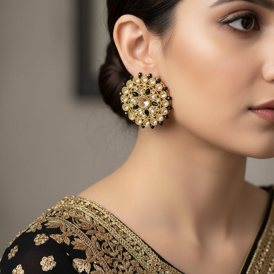 Gold and black earrings with SAHELI branding on a dark background