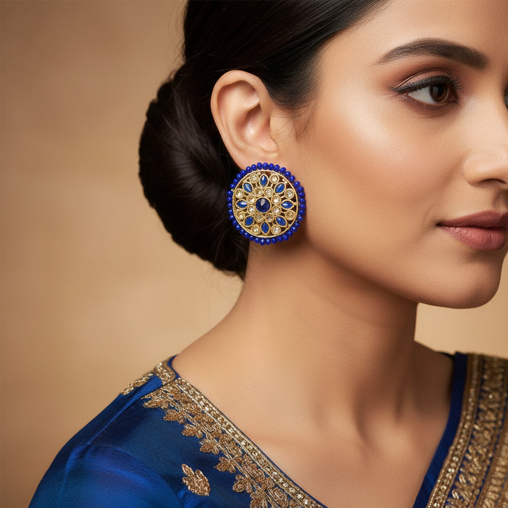 Pair of round earrings with blue and gold design on a gray background, branded 'SAHELI'.