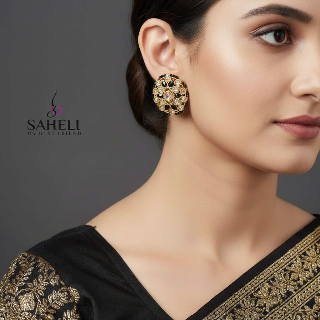 Pair of ornate earrings with gold and black design on a gray background, featuring the brand 'Saheeli'.