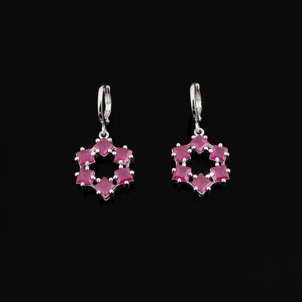 Heart-shaped earrings with pink stones on a gray background, featuring the brand 'Saheli'.