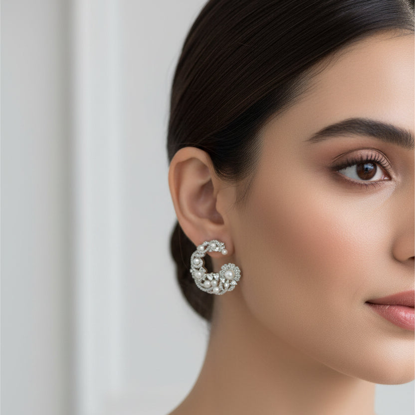 Pair of silver hoop earrings with pearls on a black background