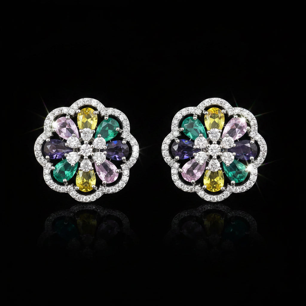 A pair of round floral stud earrings in silver-tone metal, featuring a multicolor gemstone center with yellow, green, purple, and pink stones surrounded by clear crystals, set against a solid blue background.