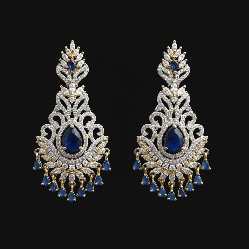 Ornate earrings with blue stones on a gray stand against a black background