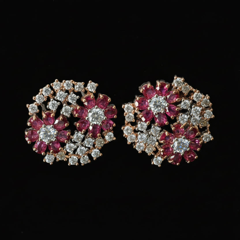 Pair of floral earrings with red and silver stones on a dark background, branded 'Saheli'.