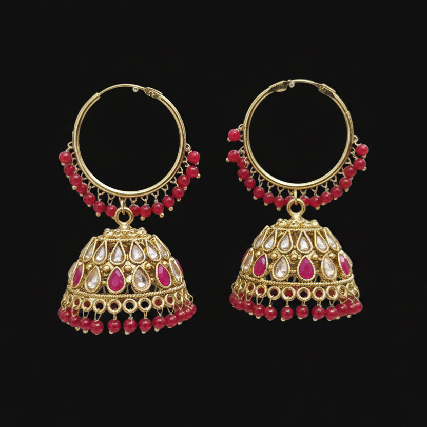 Gold and red beaded earrings on a black stand with 'SAHELI' branding.