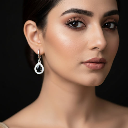 Pair of silver earrings with black gemstones on a dark gray background