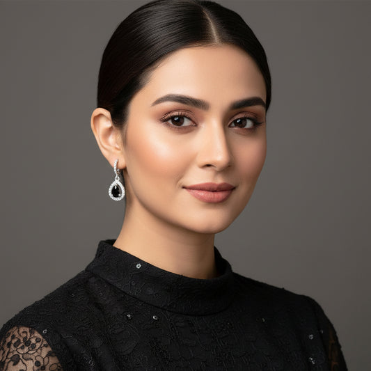 Silver earrings with black stones on a gray background, featuring the brand 'Saheili'.