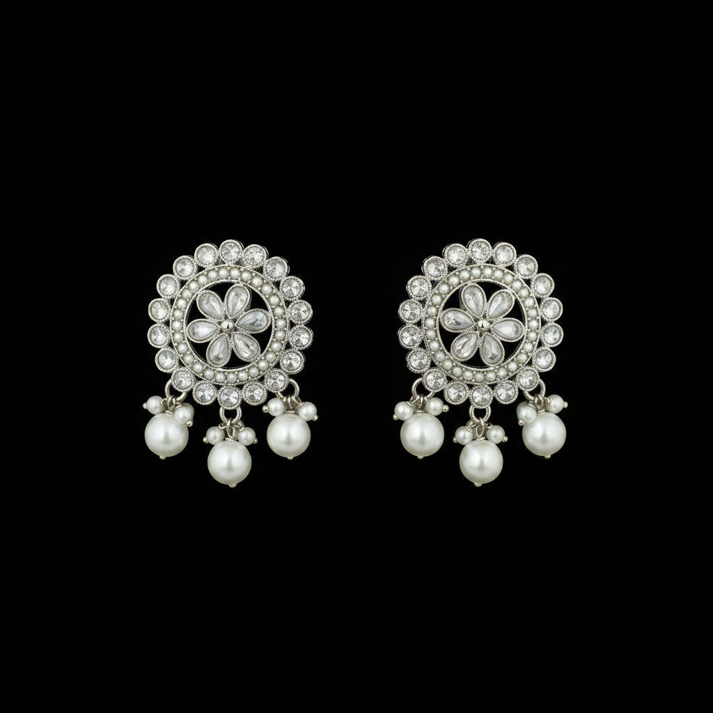 Pair of silver floral earrings with pearl beads on a black background