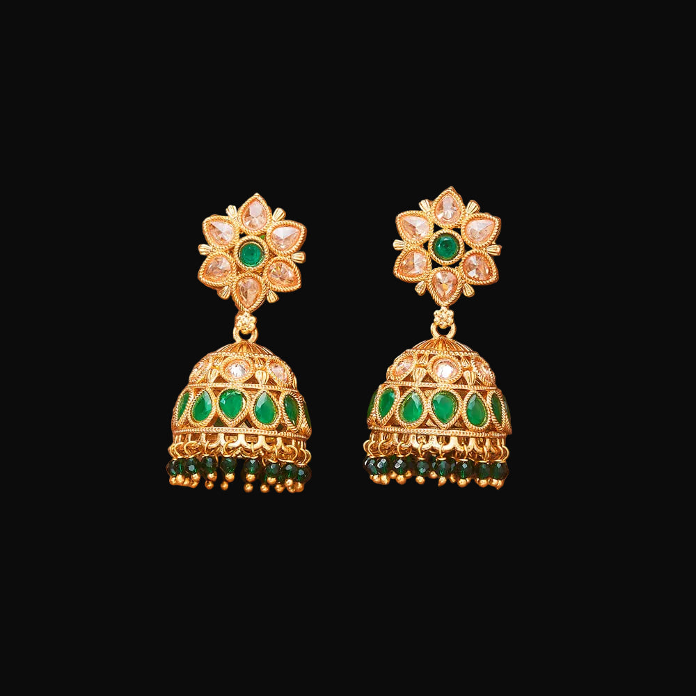 Pair of gold and green earrings on a brown background