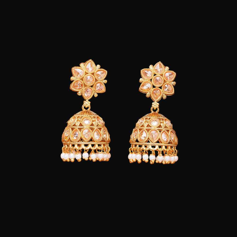 Gold earrings with floral top and bell-shaped bottom on a brown background