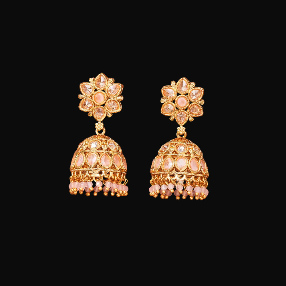 Pair of gold and pink earrings on a brown background
