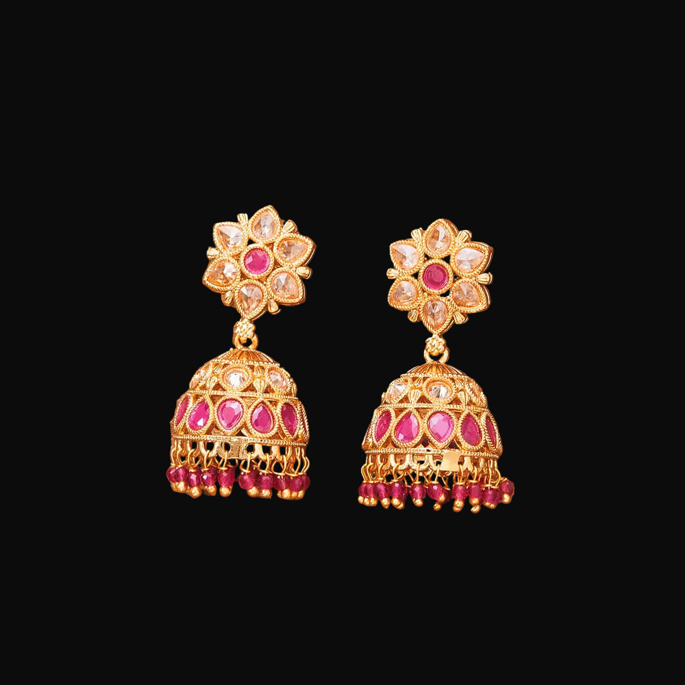 Pair of gold and pink gemstone earrings on a brown background