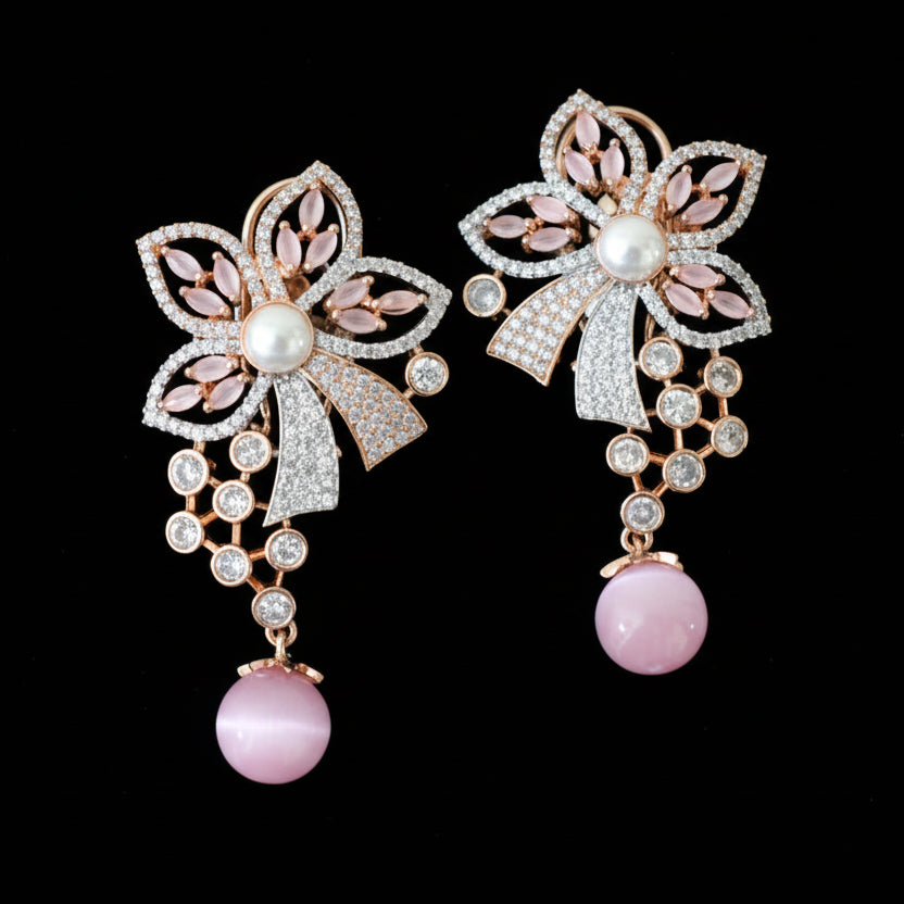 Pair of decorative earrings with floral and bow designs on a gray surface.