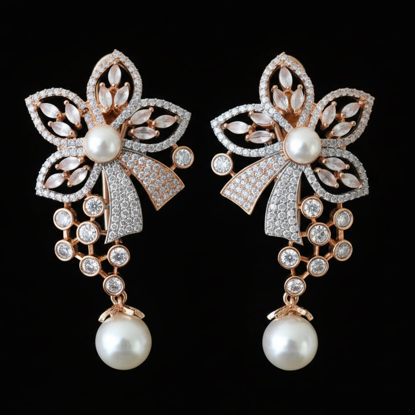 Pair of ornate earrings with floral designs and pearl-like beads on a gray surface.