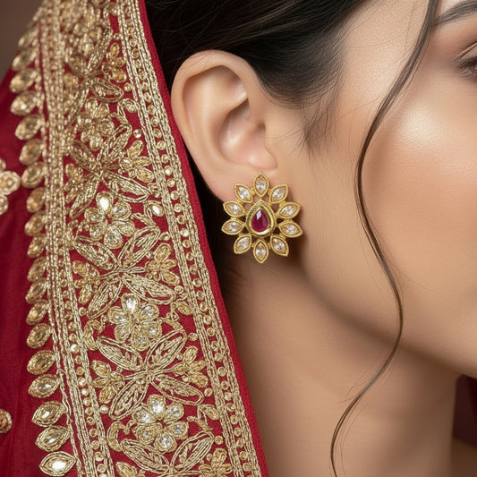 Gold floral earrings with pink gemstones on a dark background, branded 'Saheli'.