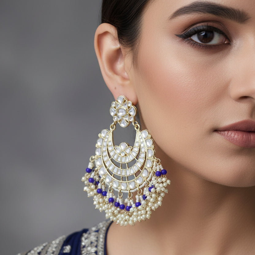 Pair of ornate earrings with blue and white stones on a dark background