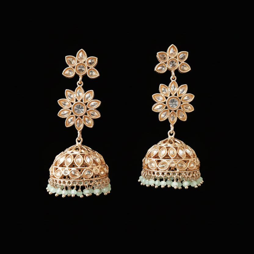 Gold floral earrings with intricate designs on a gray background, featuring the brand 'Saheli'.