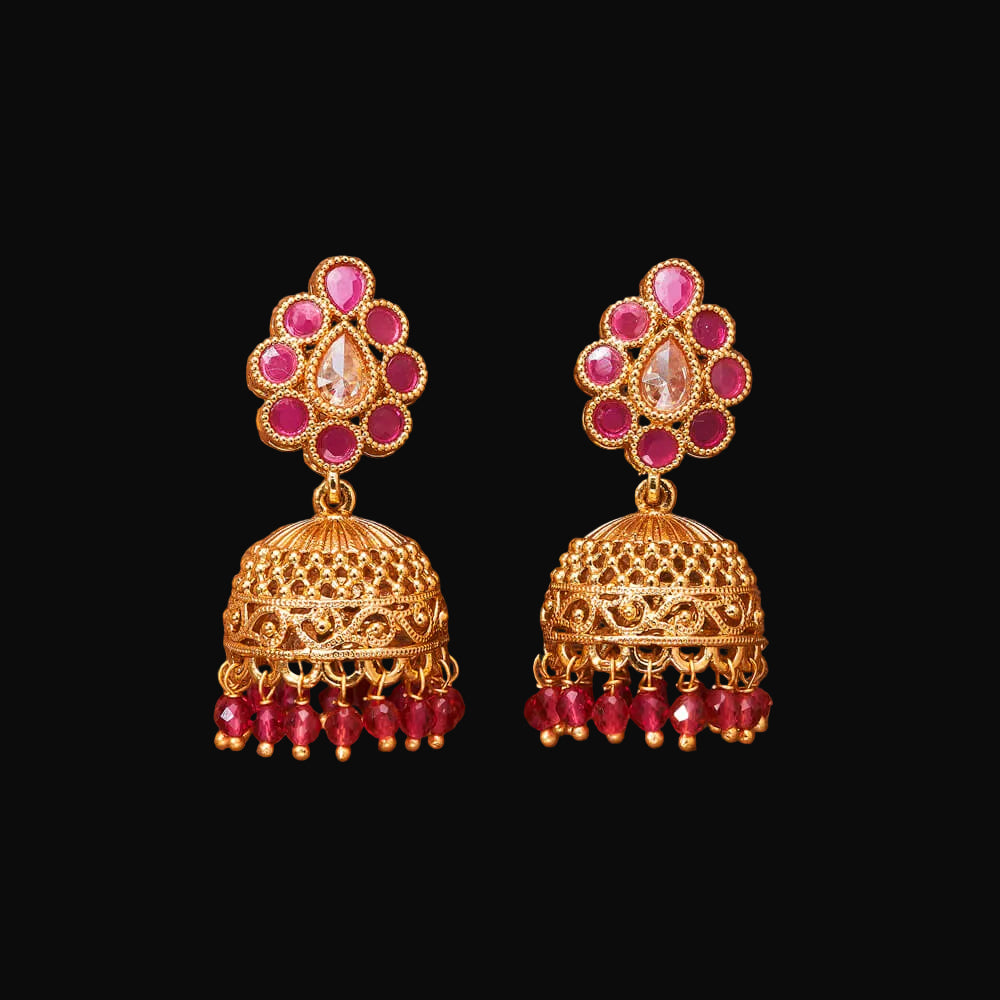 Gold and red earrings on a brown background