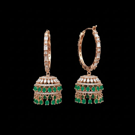 Gold and green earrings on a gray stand with 'SAHELI' branding.