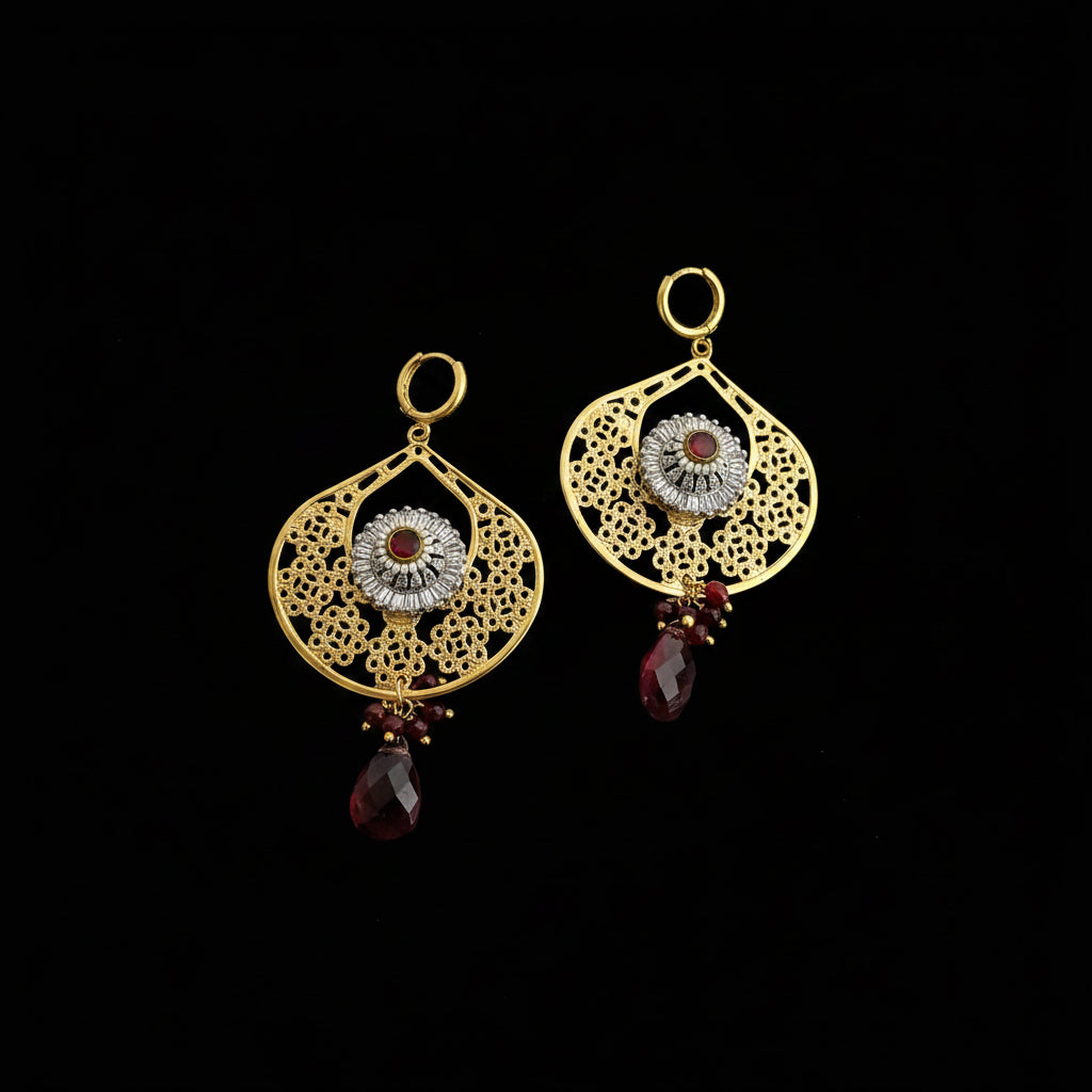 Gold earrings with red gemstones on a dark background, featuring the brand 'Saheli'.