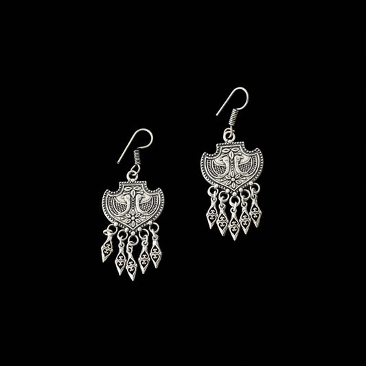 Pair of silver earrings with intricate designs on a gray background, branded 'Saheli'.