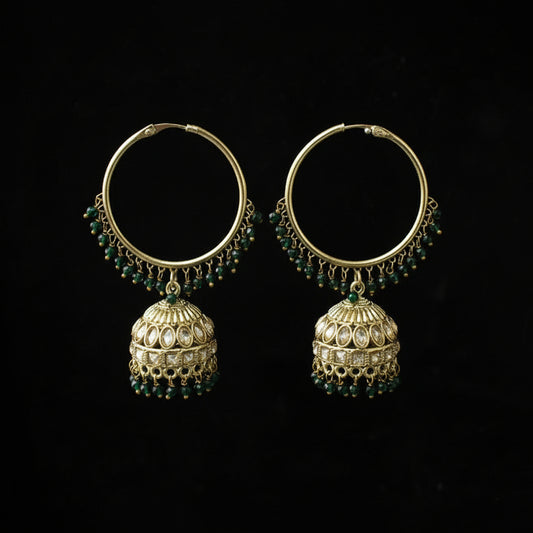 Pair of gold hoop earrings with green gemstones on a black background