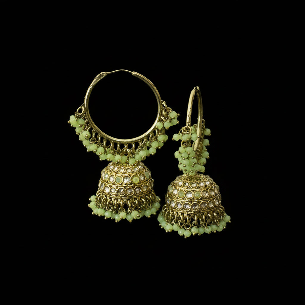 Gold and green beaded earrings on a black stand with a blurred background