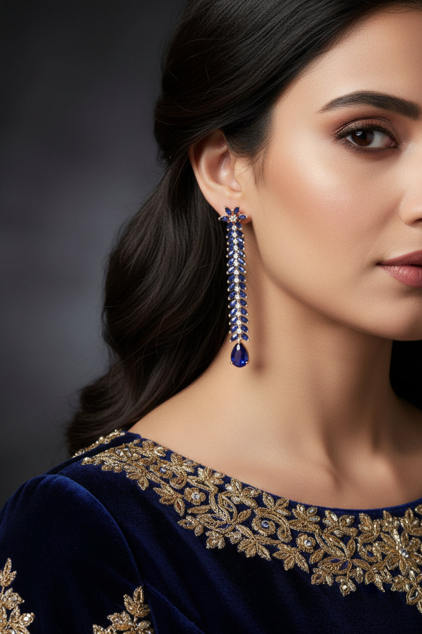 Pair of long earrings with blue gemstones on a gray background