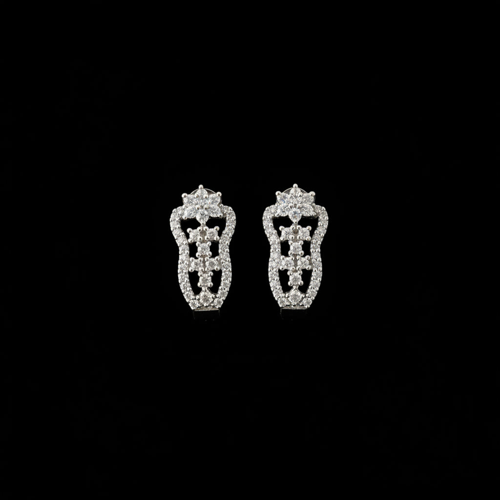 Silver earrings on a black stand with 'Saheli' branding on a dark background