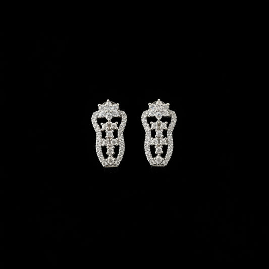 Silver earrings on a black stand with 'Saheli' branding on a dark background