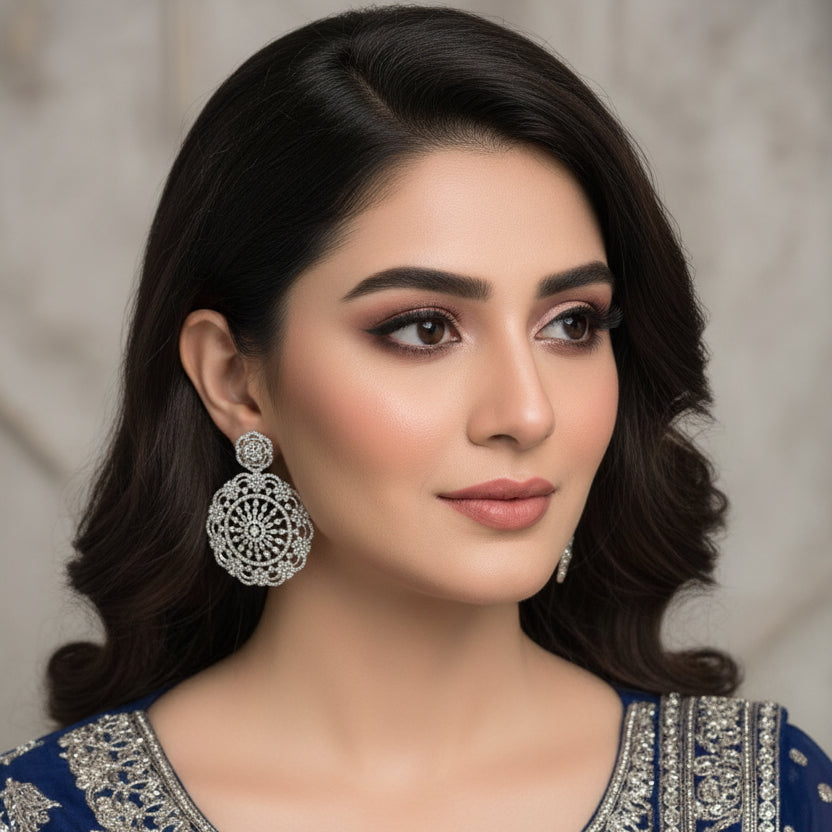 Pair of silver earrings with intricate designs on a black background