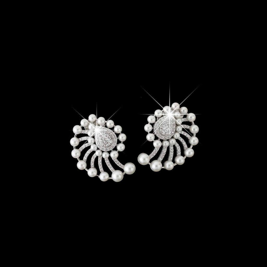 A pair of silver-toned traditional Indian earrings with white faux pearls, set against a dark reflective surface.