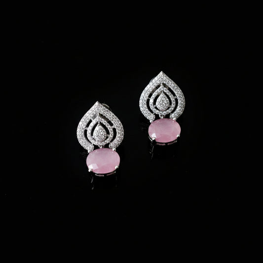 A pair of silver teardrop-shaped earrings with pavé-set clear stones and oval pink gemstone drops, displayed on a dark reflective surface.