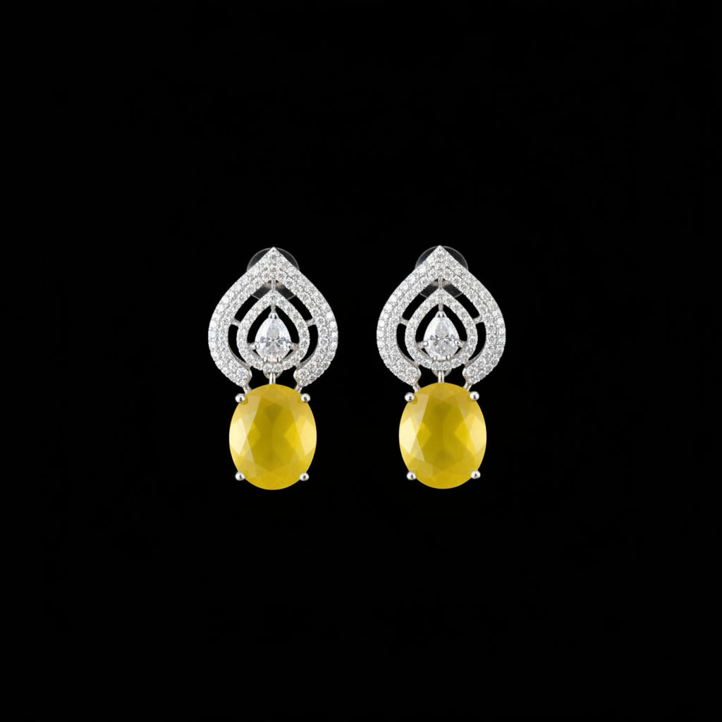A pair of teardrop-shaped earrings with silver-toned pavé settings and oval yellow gemstones, displayed on a dark reflective surface.