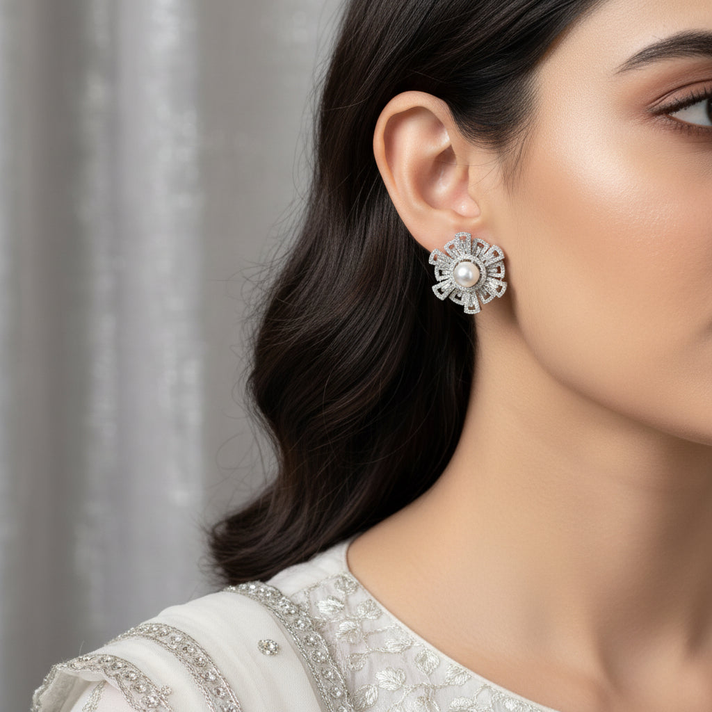 Pair of silver earrings with pearl centers on a dark background