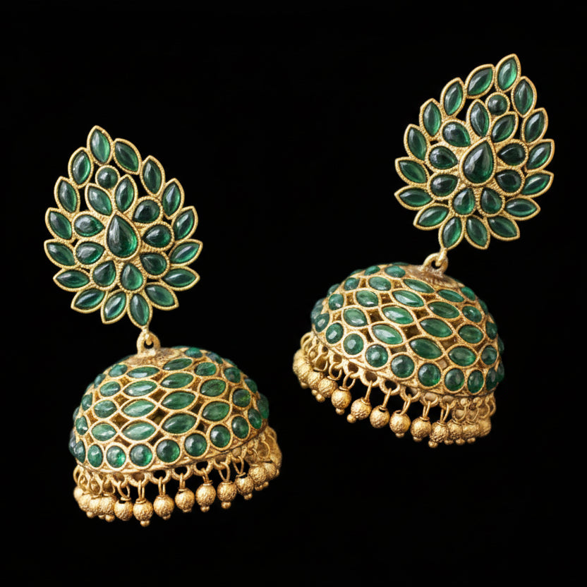 Gold and green earrings on a gray stand