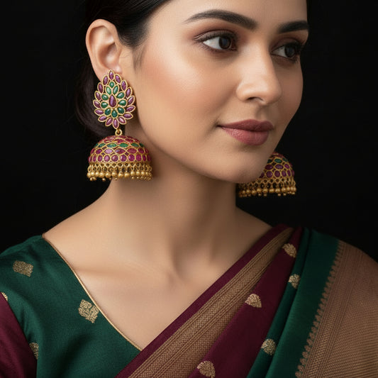 Ornate gold earrings with gemstones on a gray background