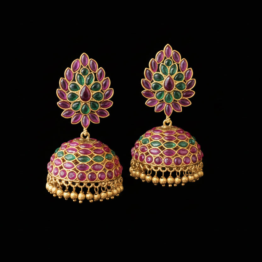 Ornate gold earrings with gemstones on a gray background