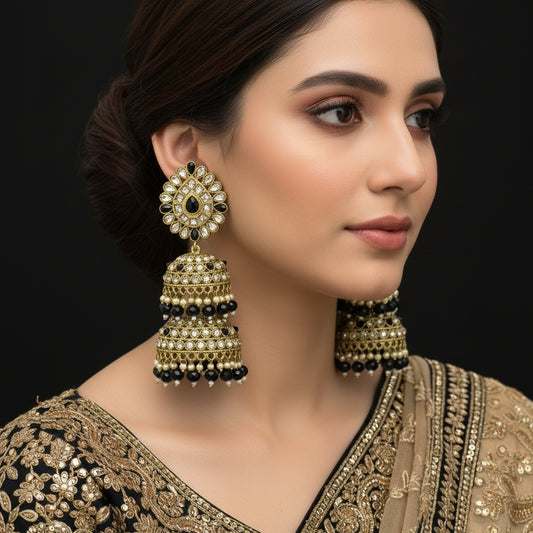 Gold and black earrings on a stand with 'Saheli' branding.