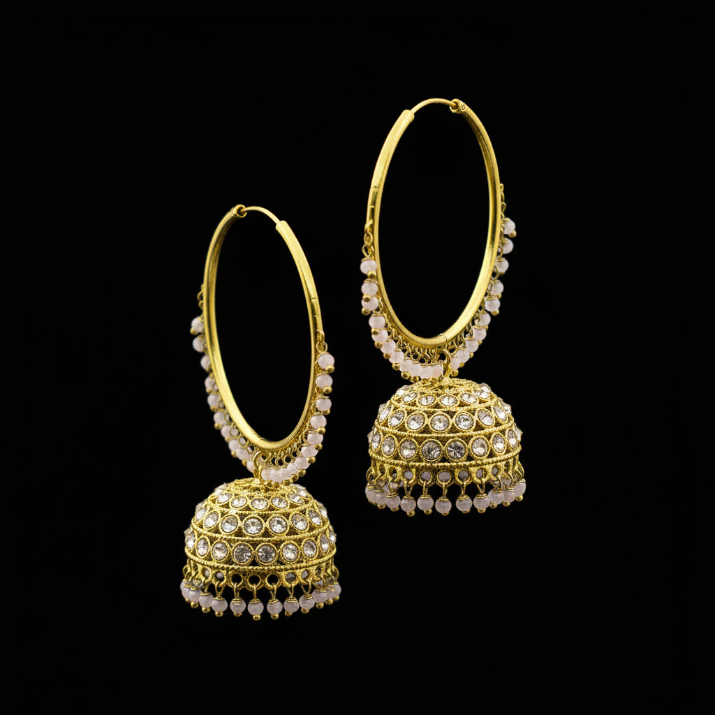 Gold hoop earrings with spherical embellishments on a black stand, branded 'Saheli'.