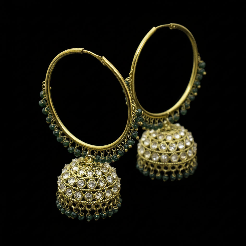 Gold hoop earrings with green and clear gemstones on a black stand against a gray background, branded 'Saheli'.