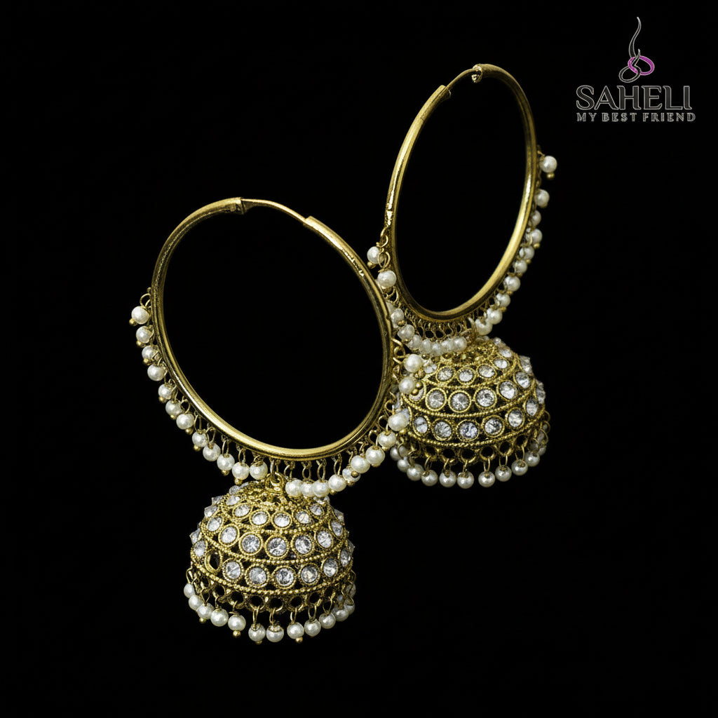 Gold and pearl earrings on a black stand with 'Saheli' branding.